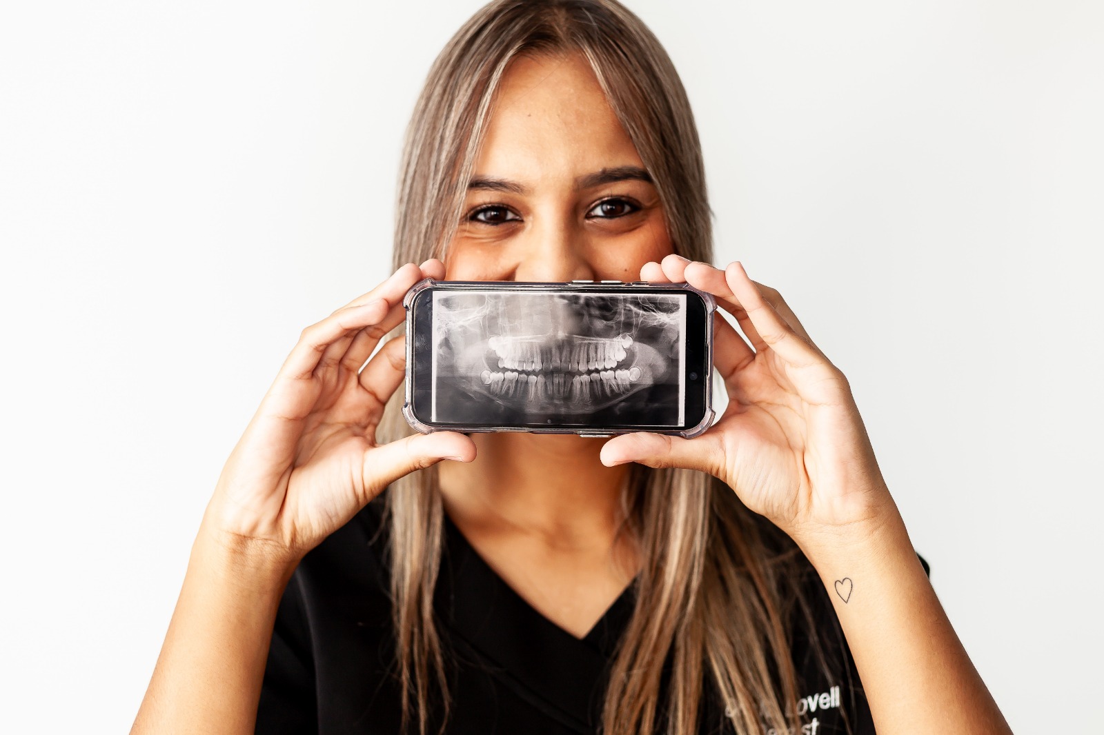 Dr Natalie Lovell holding a dental X-ray displayed on a phone