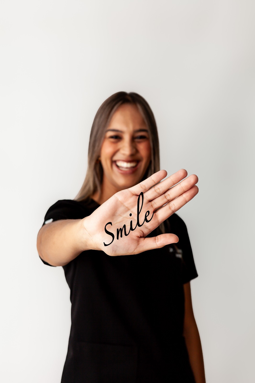 Dr Natalie Lovell smiling and holding out her hand with the word Smile written on her palm